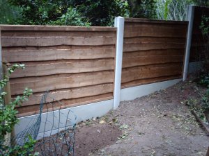 Heavy duty waney lap garden fence with concrete posts.